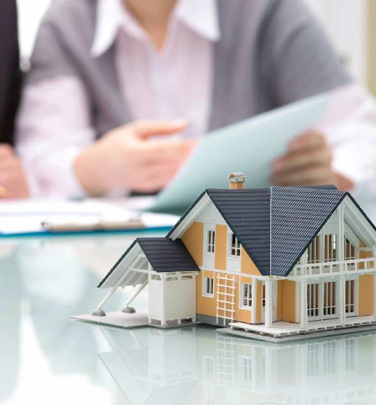 A person sitting at a table with a model house.