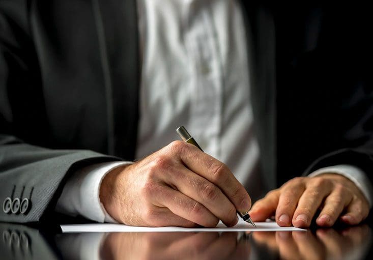 A person writing on paper with pen and ink.